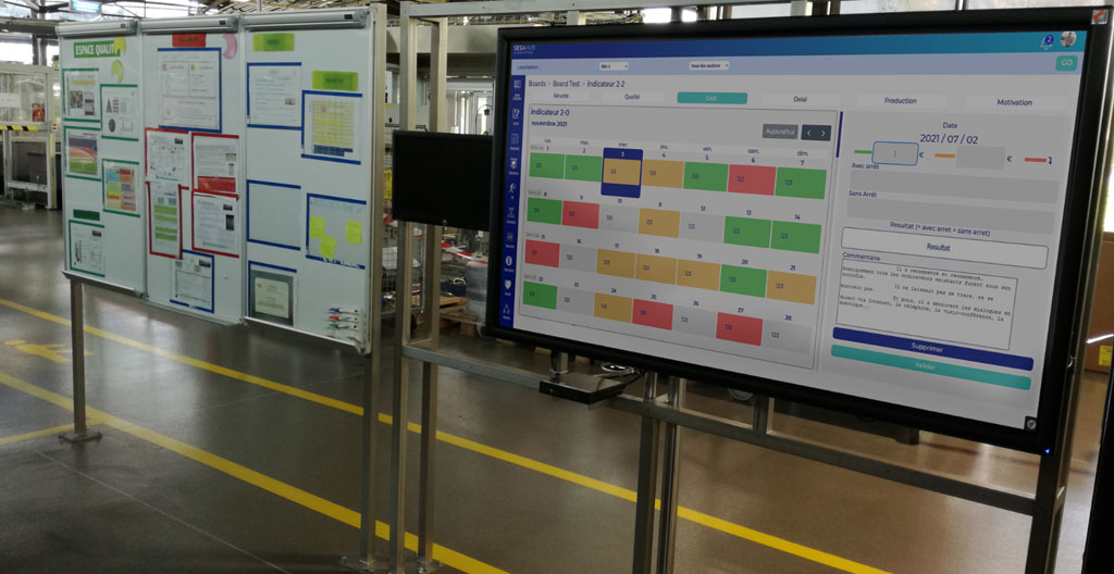 Tableau de bord avec indicateurs de performance affichés sur un écran mural dans un atelier industriel